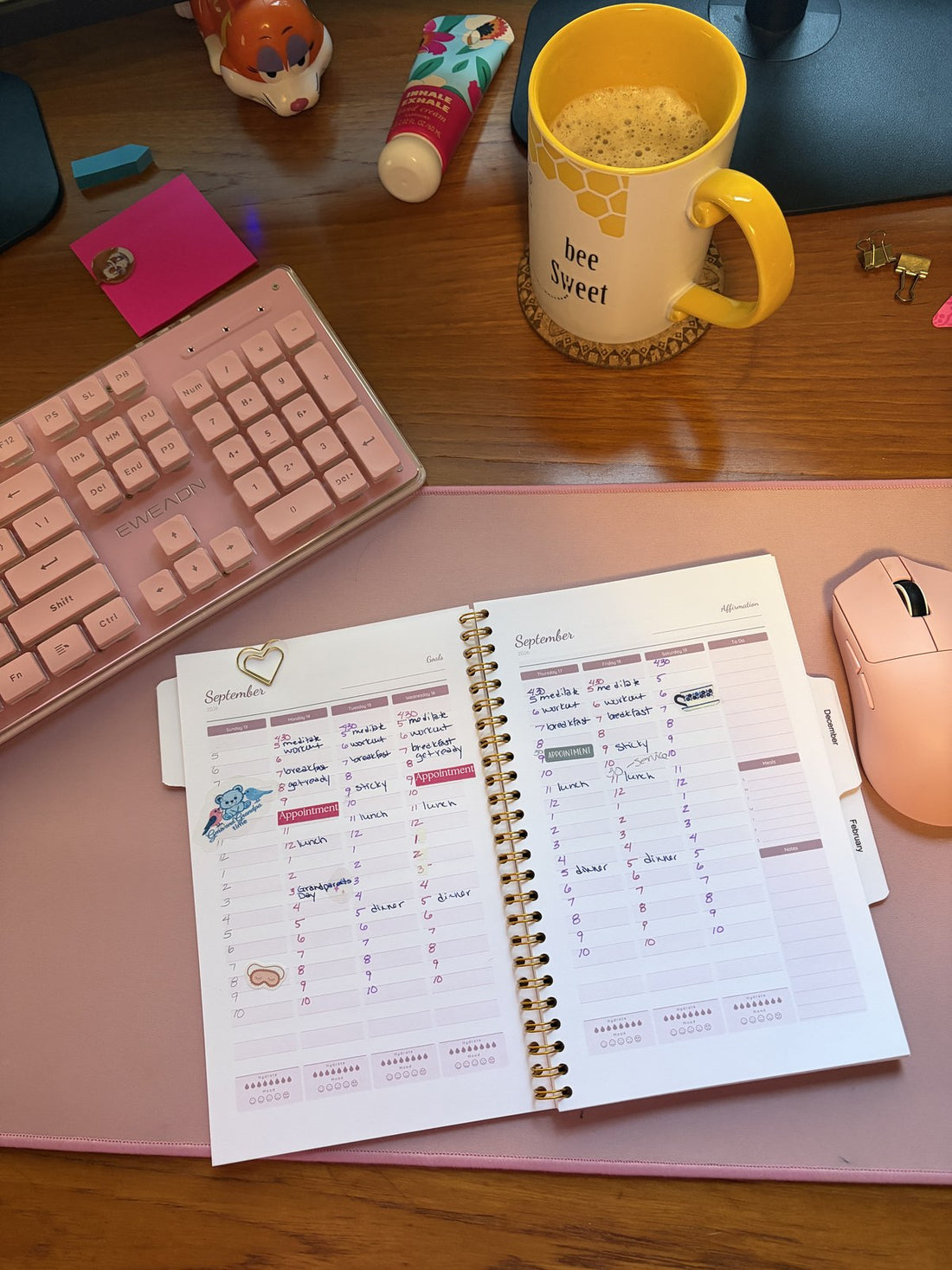 Open weekly planner spread on a pink desk mat with a handwritten morning routine, Appointment labels and a yellow bee mug